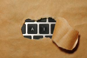 A brown paper is ripped open in the centre to reveal two keyboard keys, and A and an I.