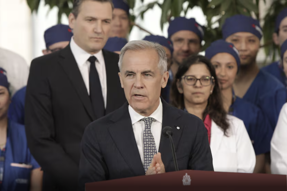 Prime Minister Mark Carney addresses a crowd at a press conference. Behind him are nurses/doctors in scrubs.